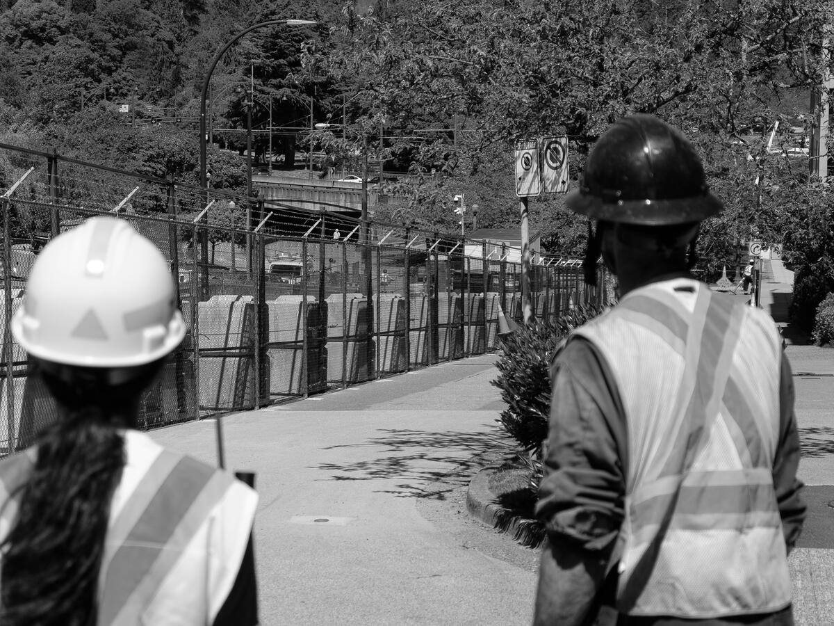 Construction crew in hard hats reviewing plans on a tablet at an active job site