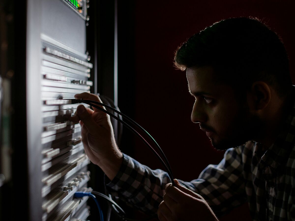 Security analyst watching alerts across several monitors in a dim operations room
