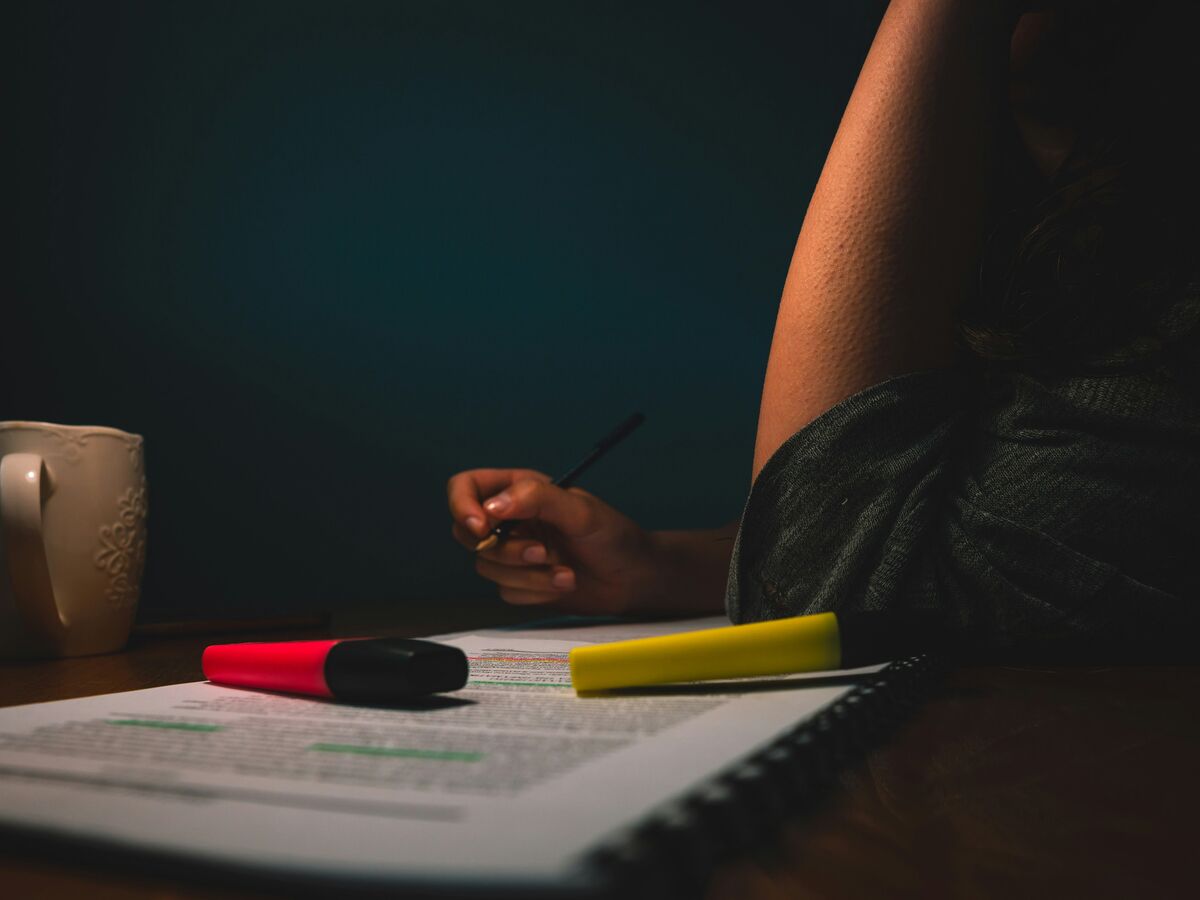 Two colleagues reviewing a printed audit report with a highlighter at a desk